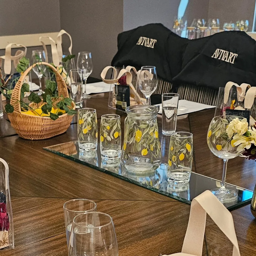 Mesa de evento com copos e jarras pintados com limões, cesta de limões e aventais da AVIVART