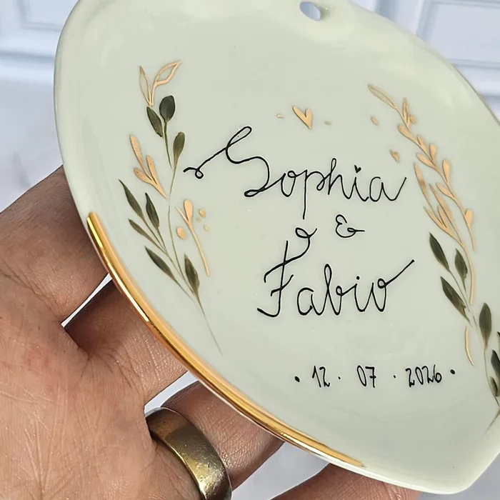 Porta-alianças em forma de coração com os nomes Sophia e Fabio e a data