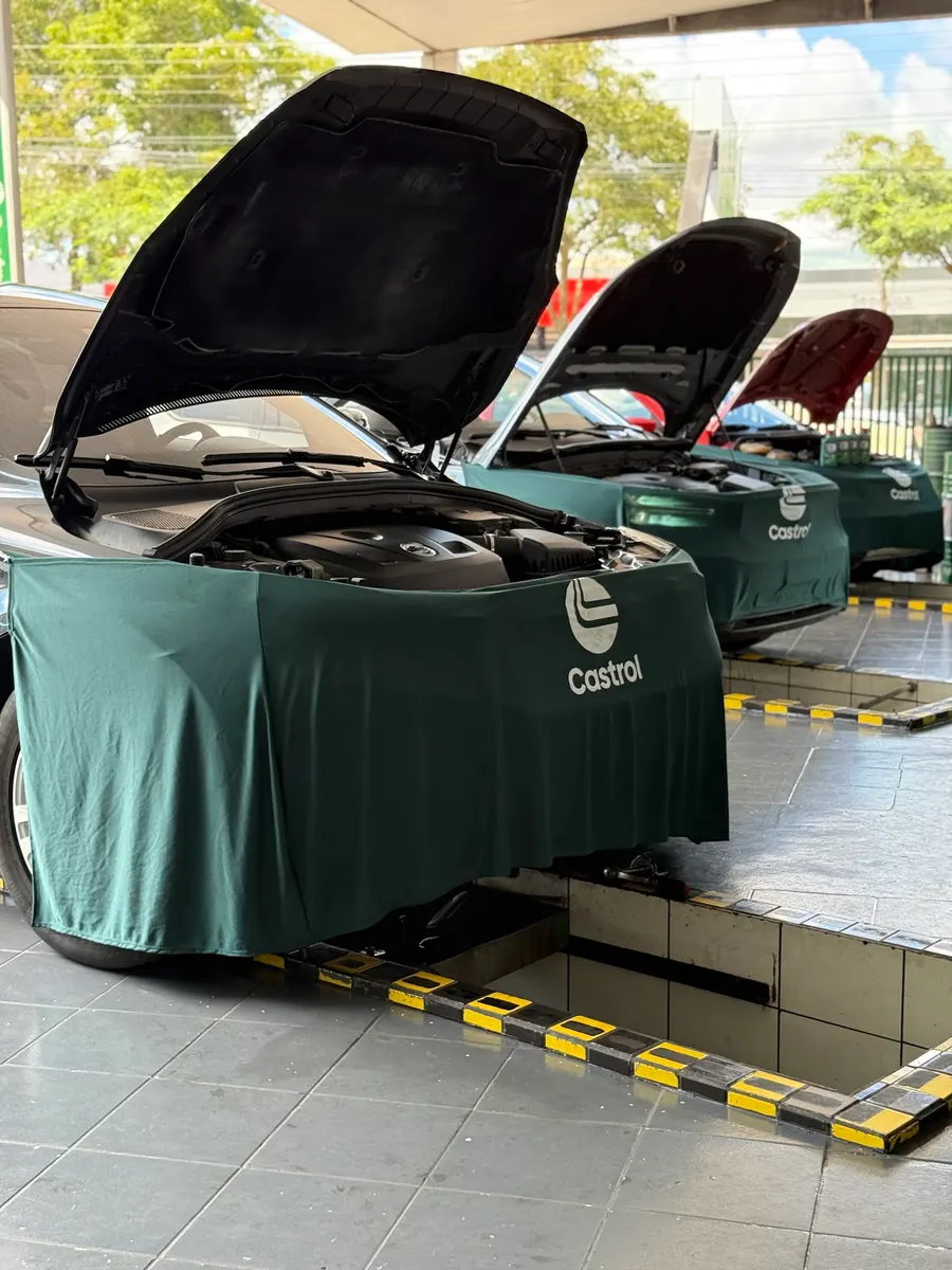 Três carros de capô aberto sobre as valas, com capa protetora na frente