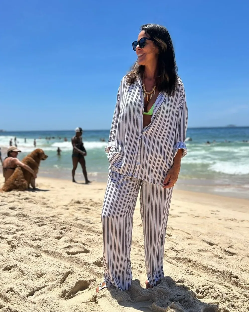 Mulher na areia da praia com conjunto listrado de viscolinho, camisa e calça