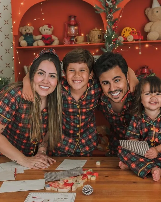 Família com duas crianças de pijama xadrez no Natal