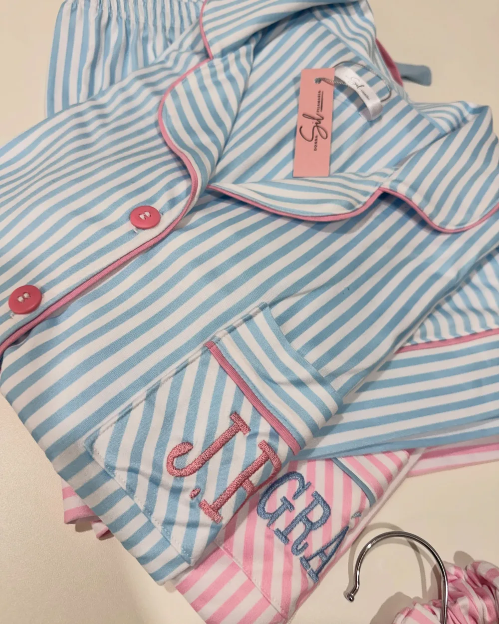 Bolso listrado azul com as iniciais bordadas em rosa e o vivo rosa